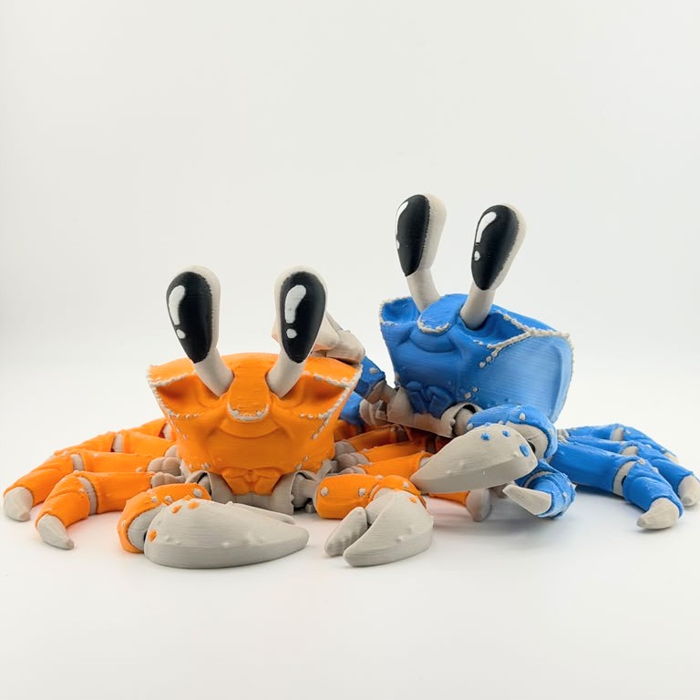 Blue and orange articulated 3D printed ghost crabs displayed together on a white background.