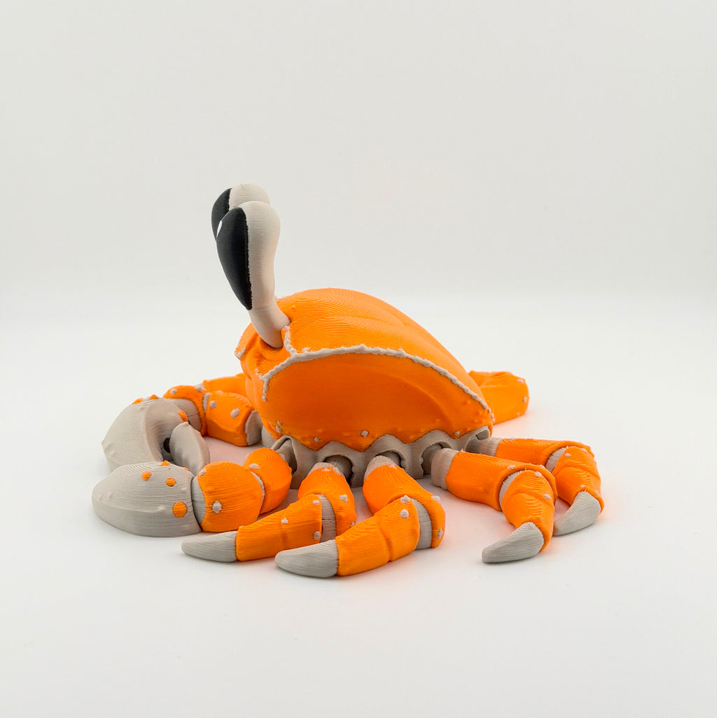 Side view of an orange articulated 3D printed ghost crab on a white background.