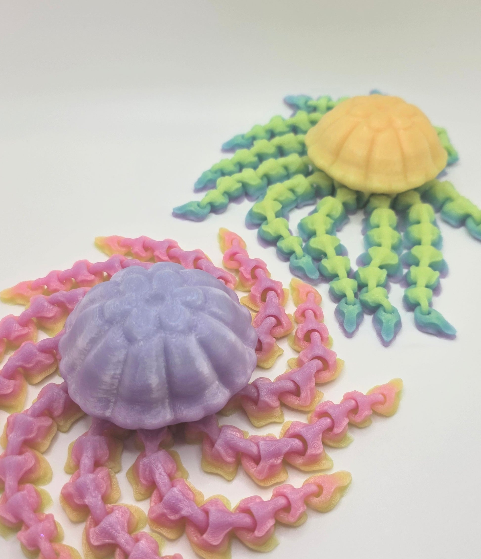 Two articulated 3D printed jellyfish displayed together in different color variations on a white background.