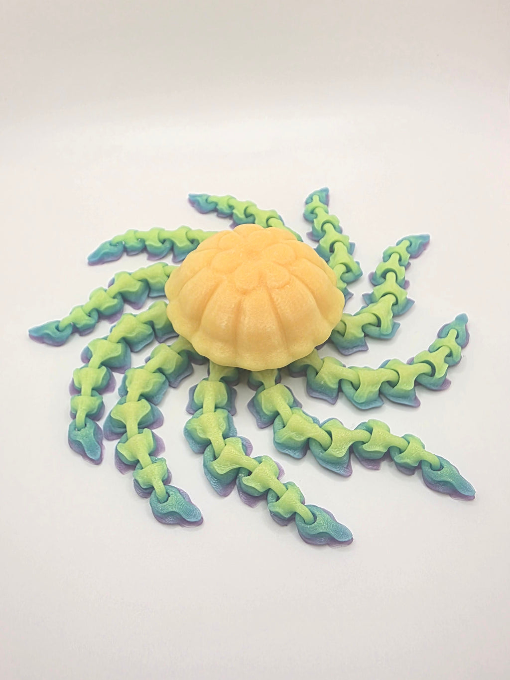 Detailed rainbow articulated 3D printed jellyfish with flexible tentacles on a white background.